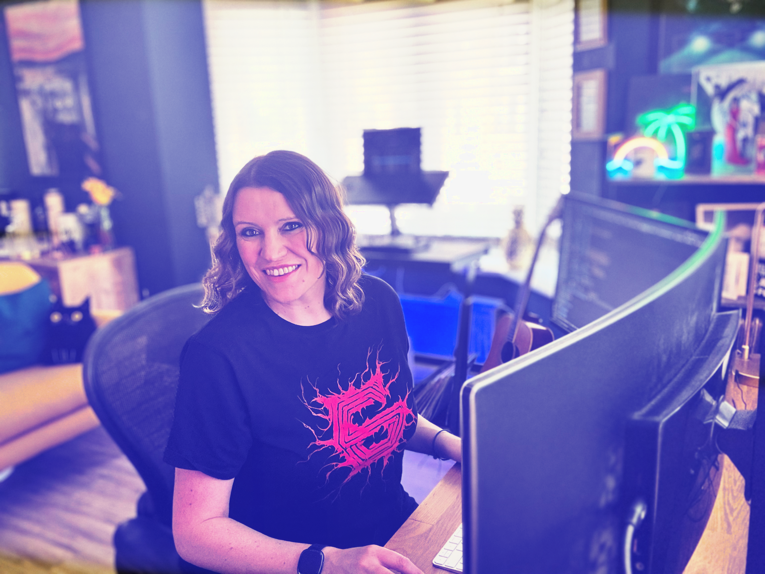 Me sat at my desk, looking at the camera smiling, wearing a Gunship t-shirt